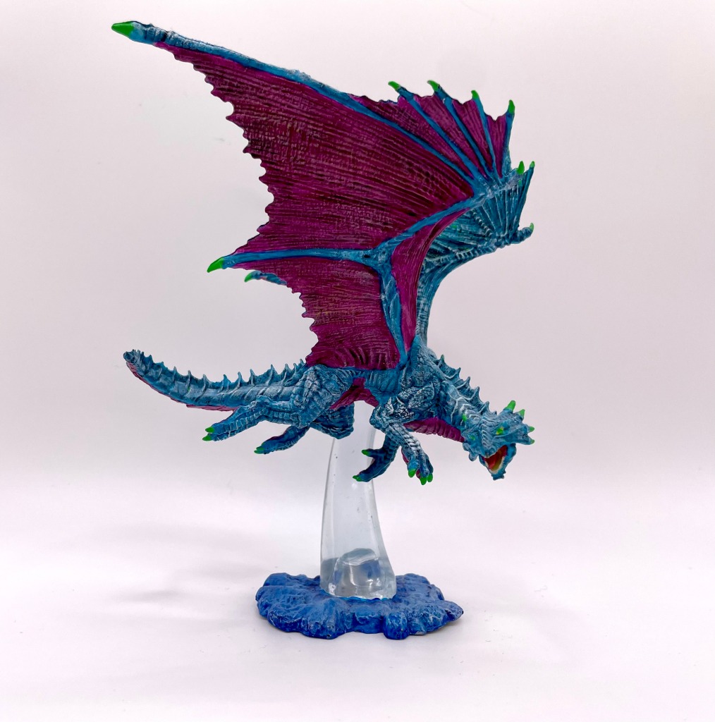 miniature blue dragon with fuchsia underbelly and wing membranes. The dragon is in a flying position.  